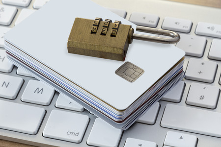Batch of Credit or debit Cards with a combination lock on a modern silver keyboardの写真素材