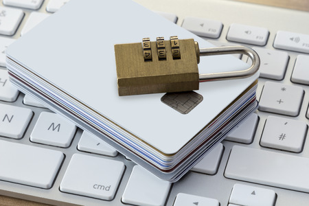Batch of Credit or debit Cards with a combination lock on a modern silver keyboardの写真素材