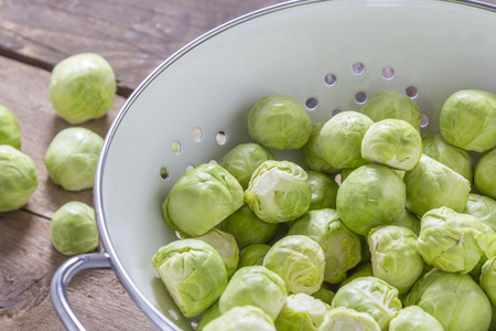 Brussels sprouts in a sieve on a wooden tableの写真素材