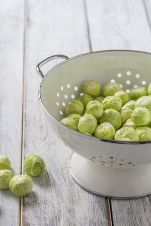 Brussels sprouts in a sieve on a wooden tableの写真素材