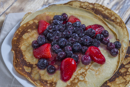 Homemade Pancakes with fresh strawberries and blueberries on a rustic wooden tableの写真素材
