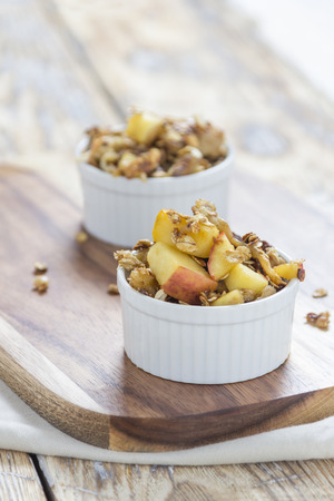 Two bowls of Apple Crumble on a wooden board on a rustic Tableの写真素材