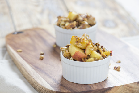 Two bowls of Apple Crumble on a wooden board on a rustic Tableの写真素材