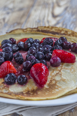 Homemade Pancakes with fresh strawberries and blueberries on a rustic wooden tableの写真素材