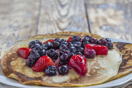 Homemade Pancakes with fresh strawberries and blueberries on a rustic wooden tableの写真素材