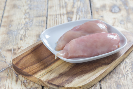 Two pieces of chicken breast fillet on a plate on a rustic wooden tableの写真素材