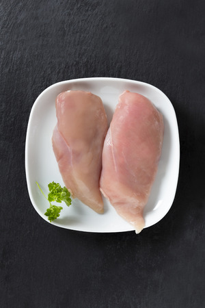 Two pieces of chicken breast fillet on a slate plateの写真素材