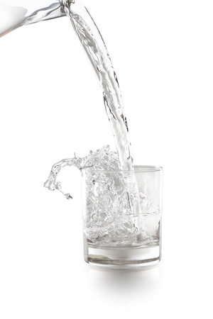 Water pouring into a glass isolated on white backgroundの写真素材