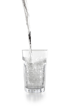Water pouring into a glass isolated on white backgroundの写真素材