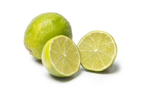 A Lime cut in two halfs and a whole lime isolated on white backgroundの写真素材