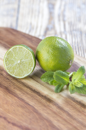 A Lime cut in two halfs and a whole lime on a rustic wooden tableの写真素材