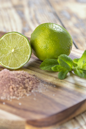 Lime mint and brown sugar the ingredients for a Mojito Cocktail on a rustic wooden tableの写真素材