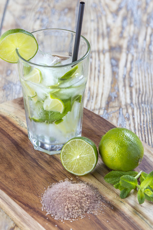 Glass with Mojito Cocktail and its ingredients on rustic wooden tableの写真素材