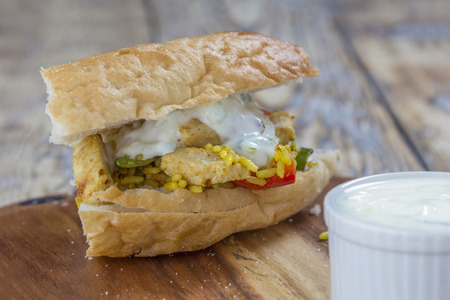 flat bread filled with chicken rice salad and yoghurt garlic dip on a rustic wooden tableの写真素材