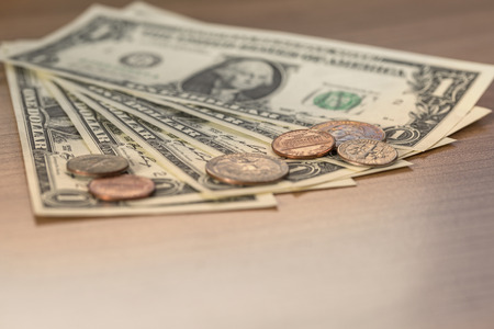 Closeup of Dollar Notes and Coins on a wooden table