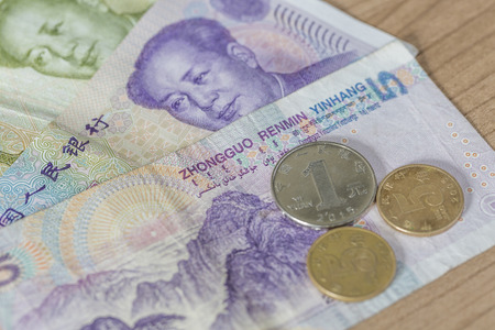 Chinese Renminbi (also called Yuan) banknotes and coins on a wooden tableの写真素材