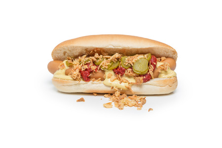 Hot Dog sausage in a bun with roasted onions, pickles, ketchup and mustard on white backgroundの写真素材