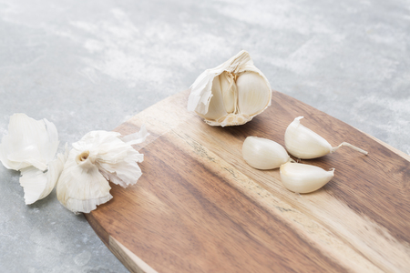 Garlic bulb and single cloves on a wooden boardの写真素材