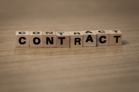 Contract written in wooden cubes on a deskの写真素材