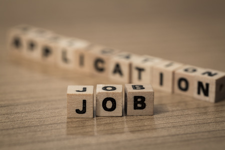 Job Application written in wooden cubes on a deskの写真素材