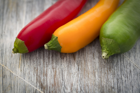 Closeup of red yellow and green Chilli on rustic wooden tableの写真素材