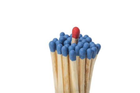 Red Match sticking out of a group of blue matches isolated on white backgroundの写真素材