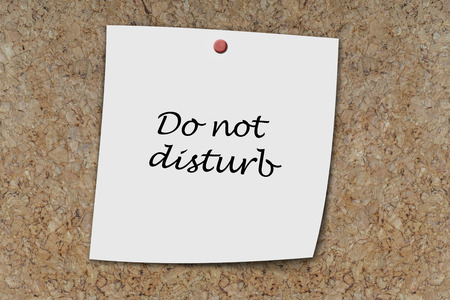 do not disturb written on a memo pinned on a cork boardの写真素材