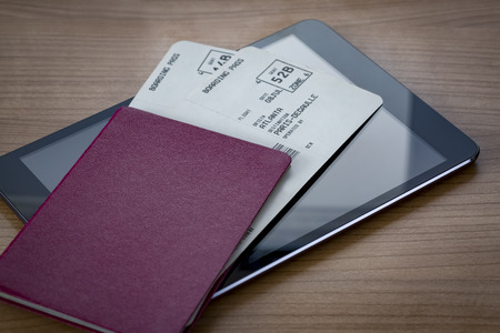 Unmarked red passport with two flight tickets on a tablet pcの写真素材