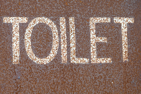 The word toilet on a rusted steel plate.の写真素材
