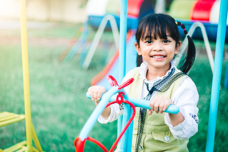 Little girl playing and smiling on the playground with sunlight.の写真素材