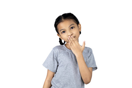 Little Asian girl covered her mouth with her right hand isolated on white background with clipping path.の写真素材