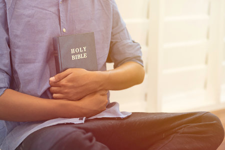 Man hugging the bible in the morning with sunlight.
