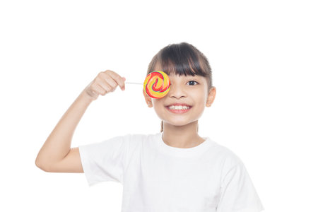 Young Asian girl smiles and holding lollipop candy isolated on white background with clipping path.の写真素材