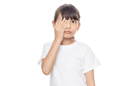 Young Asian girl has sore eye isolated on white background with clipping pathの写真素材