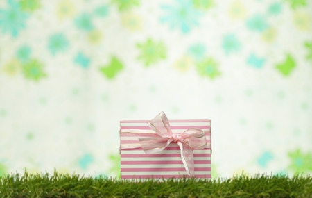 Gift box resting on grass background pin flowers