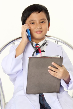 Future Doctor Smile on the face of a 10 year old boy dressed as a doctor holding Tablet and Mobile phone の写真素材