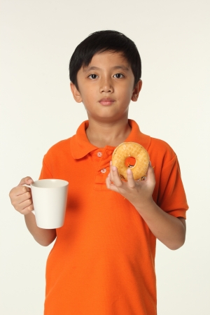 Kit eating dough nut with hot drink  の写真素材