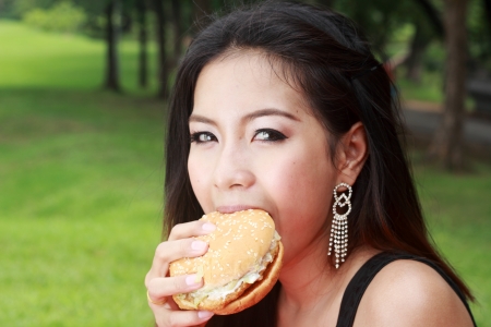 Teenage Girl Eating a Cheeseburger in the parkの写真素材