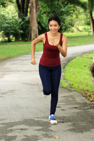 Asian woman running in park in sunshine on the holidayの写真素材