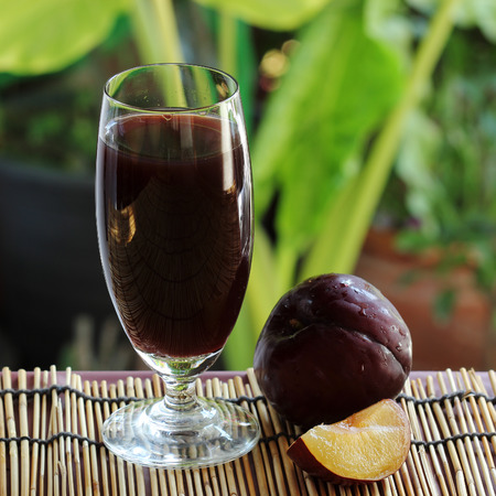 Fresh plums and a glass full of plums juice の写真素材