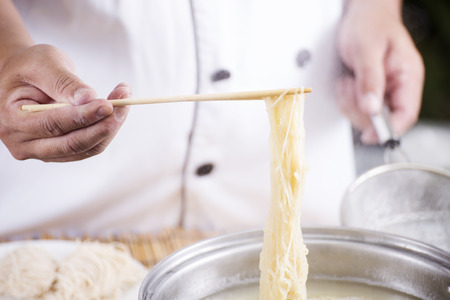 Chef holding the noodle from the pot with chopsticks  / Cooking Noodle conceptの写真素材