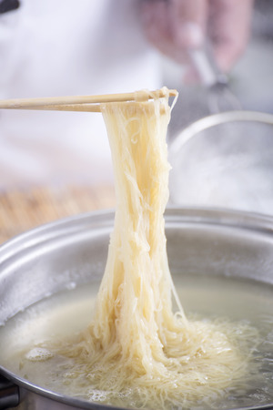 Chef holding the noodle from the pot with chopsticks  / Cooking Noodle conceptの写真素材