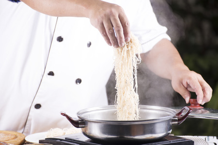 Chef putting the noodle to the pot / Cooking Noodle conceptの写真素材