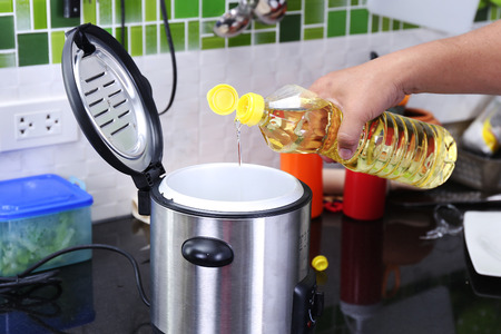 Chef pouring vegetable oil to the electronic potの写真素材