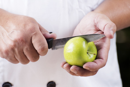 Chef cutting green apple on his hand