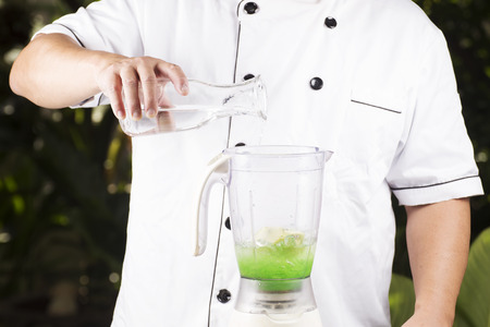 Chef pouring water to the Blender for making green apple smoothieの写真素材
