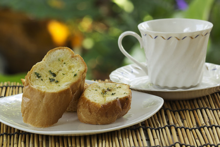 Garlic bread on the plate with cup of tea