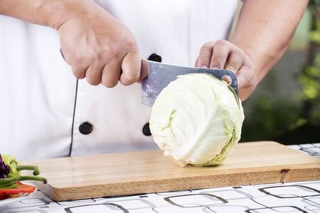 Chef cutting cabbage on the wooden broadの写真素材