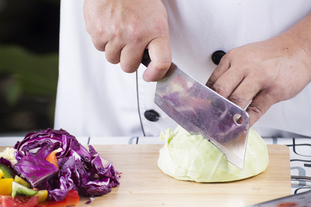 Chef cutting green cabbage on wooden broadの写真素材