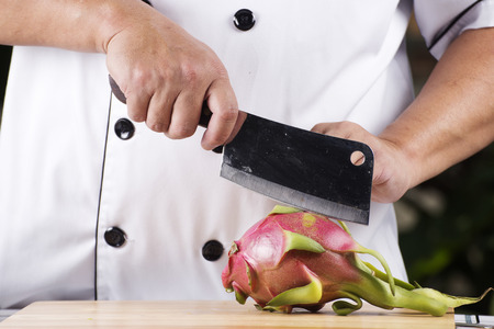 Chef cutting dragon fruit on wooden broadの写真素材